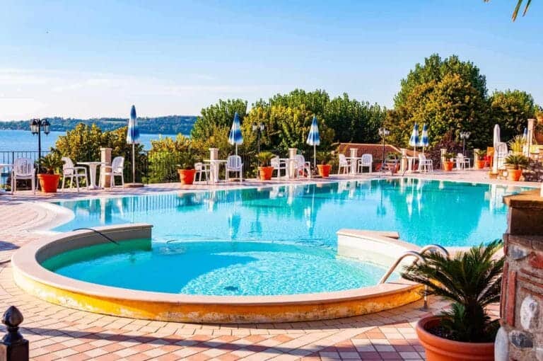Camping i Italien, La Ca, Garda Lake, Lombardy, Italy - September 12, 2019: Outdoor pool with vibrant crystal water, parasols and deck chairs located on the coast of Garda lake in amazing La Ca camping in Italy