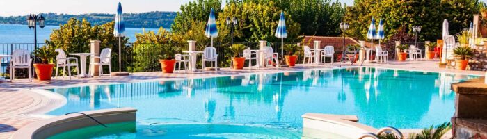 Camping i Italien, La Ca, Garda Lake, Lombardy, Italy - September 12, 2019: Outdoor pool with vibrant crystal water, parasols and deck chairs located on the coast of Garda lake in amazing La Ca camping in Italy