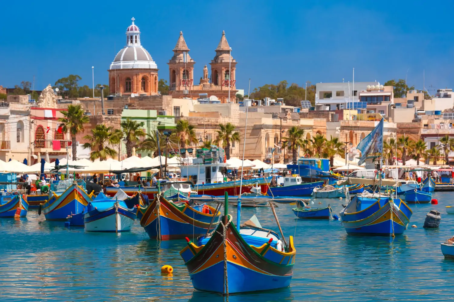 Malta, Traditional eyed colorful boats Luzzu in the Harbor of Mediterranean fishing village Marsaxlokk, Malta