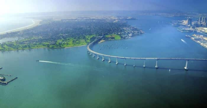 Aerial view of the Coronado island and bridge in the San Diego Bay in Southern California, United States of America. A view of the Skyline of the city and some boats crossing the the sea.