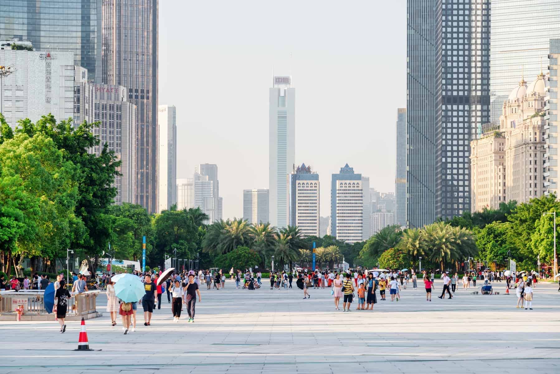 Guangzhou, China : Asian tourists walking in a scenic city park among modern buildings in the Tianhe District of the Zhujiang New Town. Guangzhou is a popular tourist destination