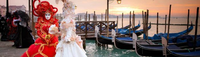 Karneval i Venedig. Sunrise in Venice Italy in front of Gondolas on the Grand Canal Beautiful costumed women