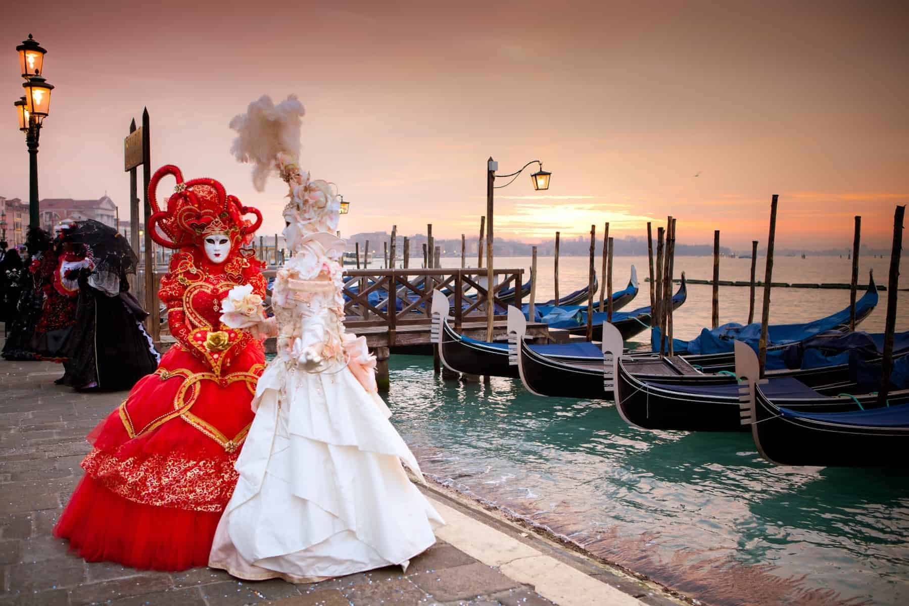 Karneval i Venedig. Sunrise in Venice Italy in front of Gondolas on the Grand Canal Beautiful costumed women