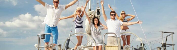smiling friends sitting on yacht deck and greeting
