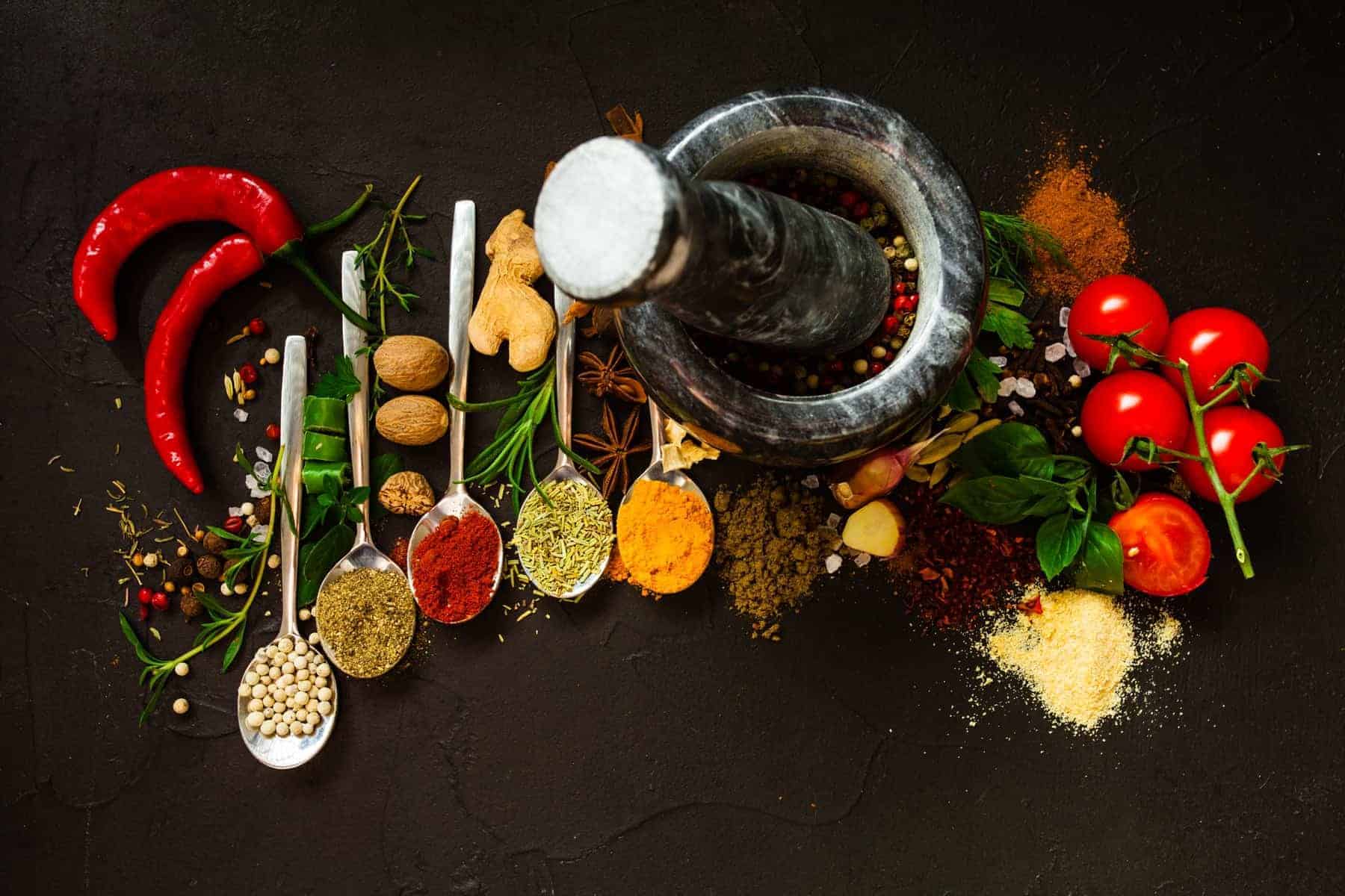 Pepper in a mortar and dry spices on a black background