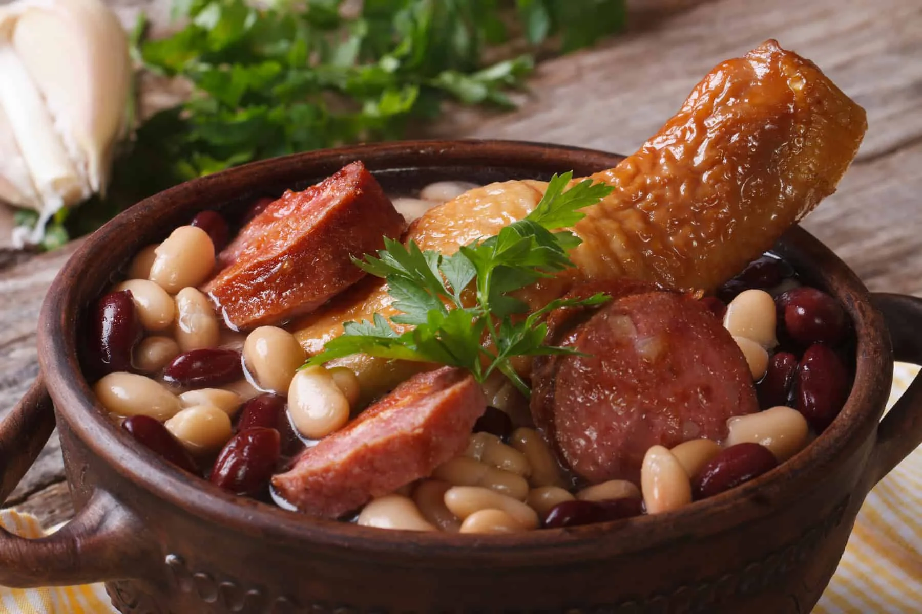Cassoulet. Beans with chicken legs and grilled sausages close up horizontal