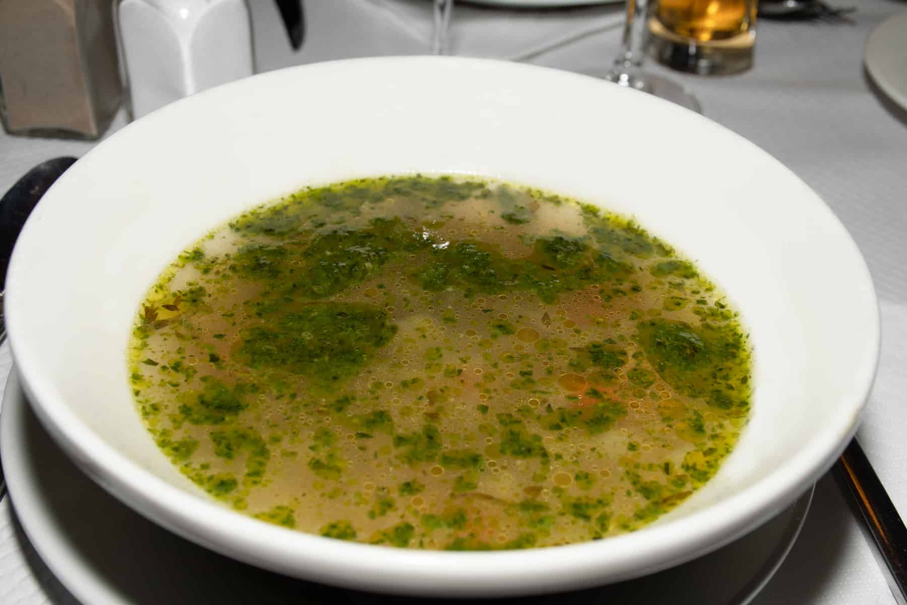 Soup au pistou (pesto) in a white bowl being served in a restaurant. traditional authentic