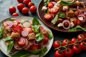 Panzanella, fresh Italian vegetable salad served on plates on table with tomatoes