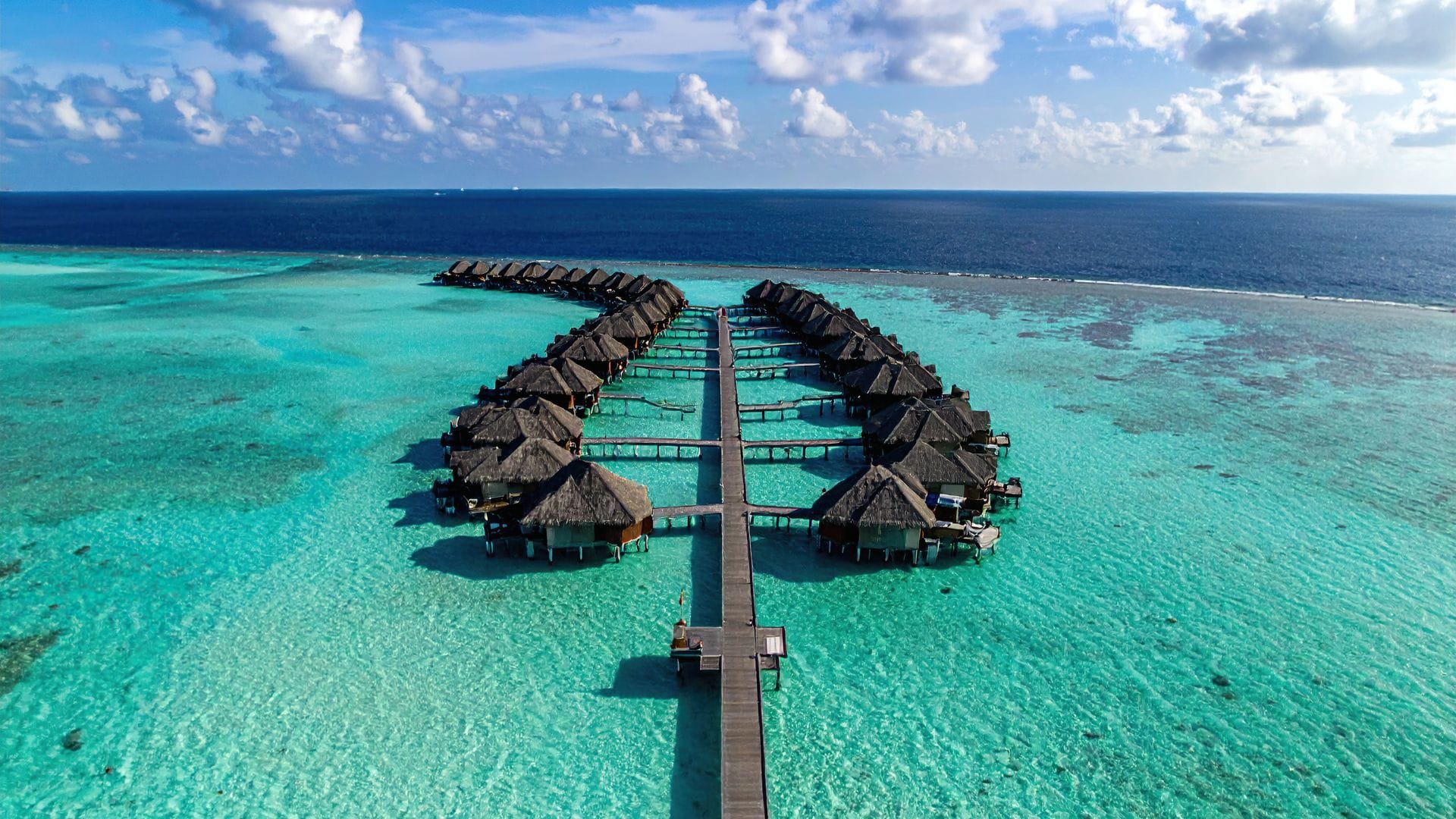 Luftfoto af Maldiverne med turkis lagune og overwater bungalows – et af verdens mest ikoniske tropeparadiser
