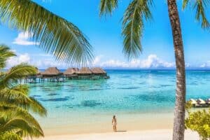 Det tabte paradis i Tahiti. Luxury Tahiti beach resort travel tourist walking on Polynesian beach ocean water at overwater bungalow hotel in French Polynesia