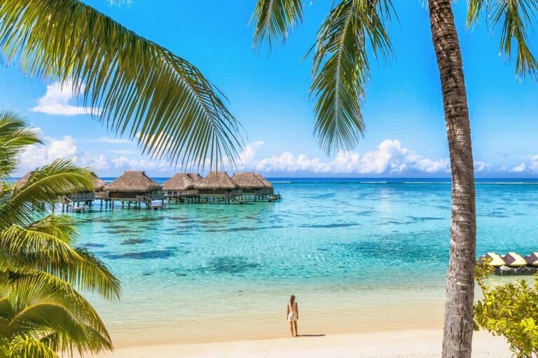 Det tabte paradis i Tahiti. Luxury Tahiti beach resort travel tourist walking on Polynesian beach ocean water at overwater bungalow hotel in French Polynesia