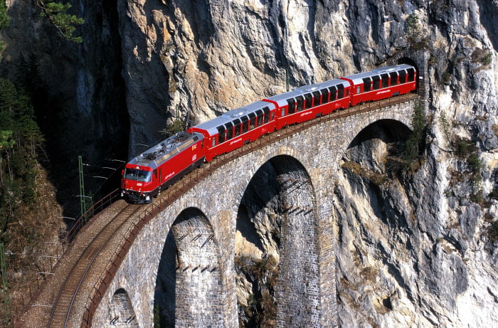 Bernina Express - The Bernina Express crosses the world-famous Landwasser Viaduct. Bernina Express - Il Bernina Express attraversa il celebre viadotto di Landwasser. Un viaggio dai ghiacciai alle palme. Copyright by Rhaetische Bahn By-line: swiss-image.ch/Peter Donatsch