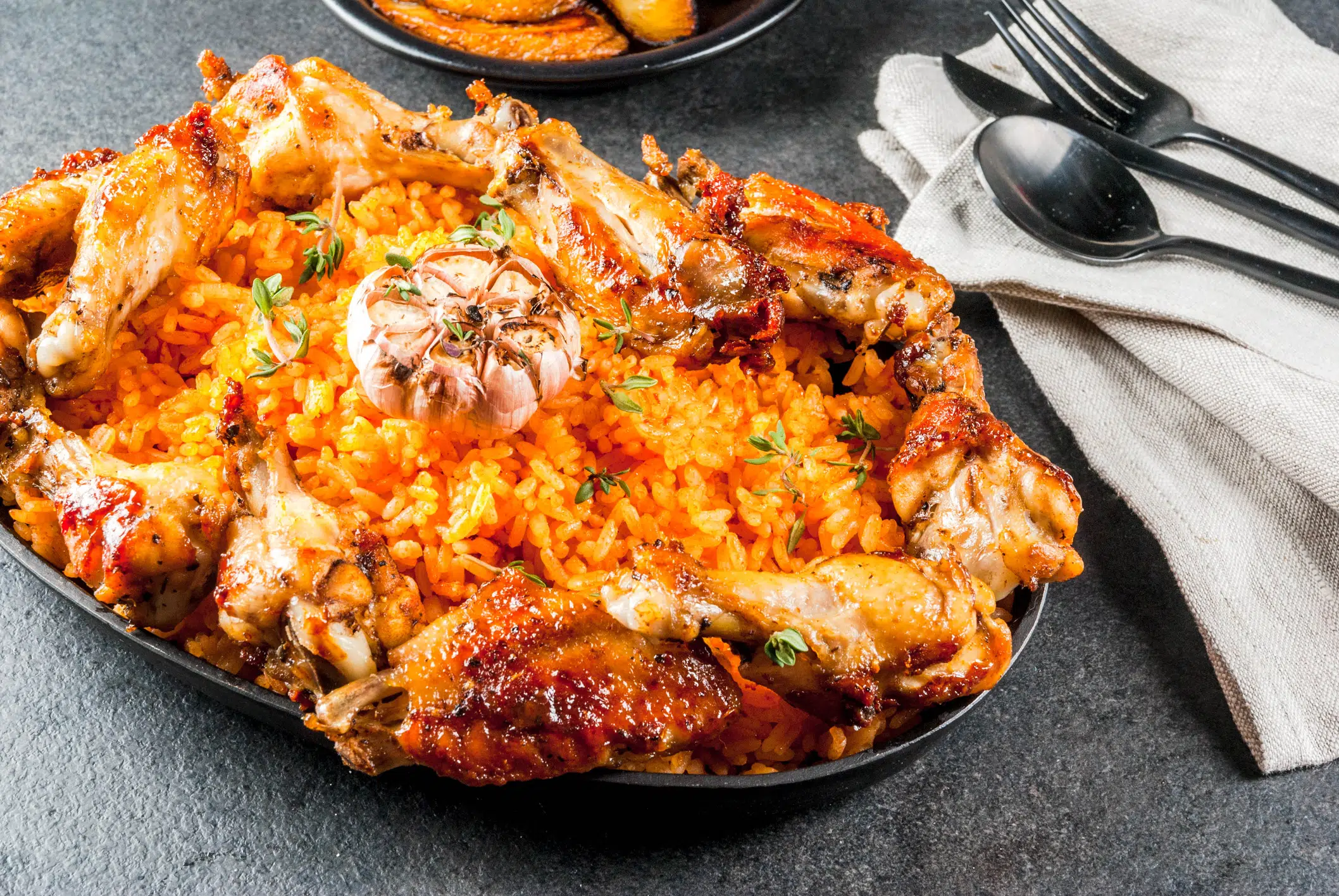 West African national cuisine. Nigeria. Jollof rice with grilled chicken wings and fried bananas plantains.