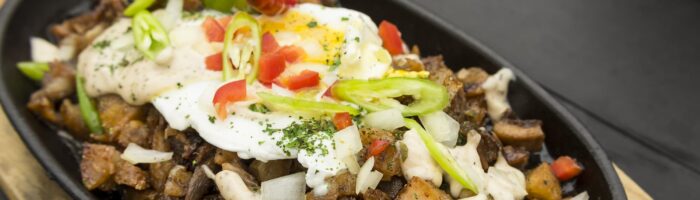Freshly cooked Pork Sisig with egg, onions and chilies. A popular Filipino dish.