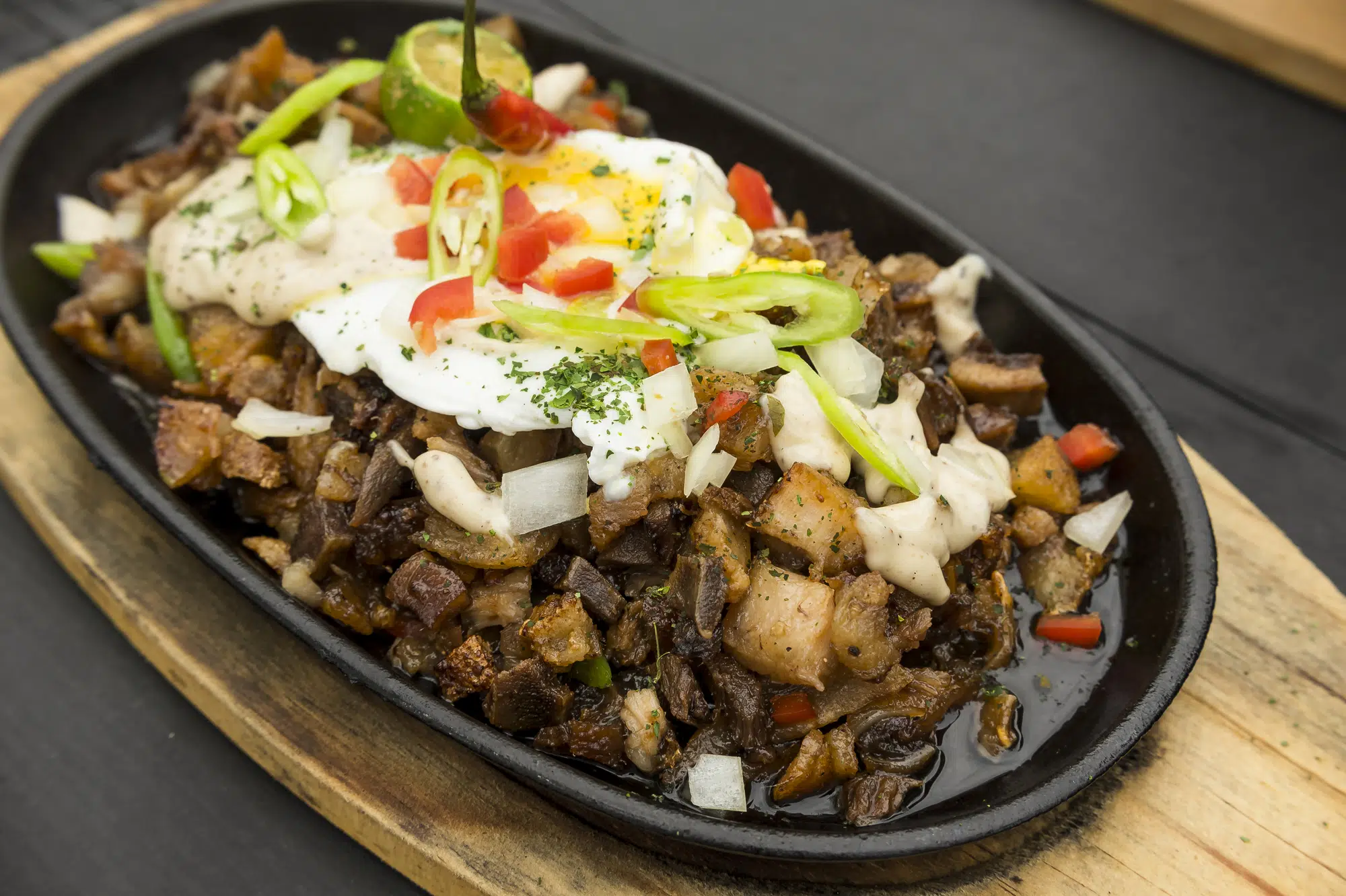 Freshly cooked Pork Sisig with egg, onions and chilies. A popular Filipino dish.