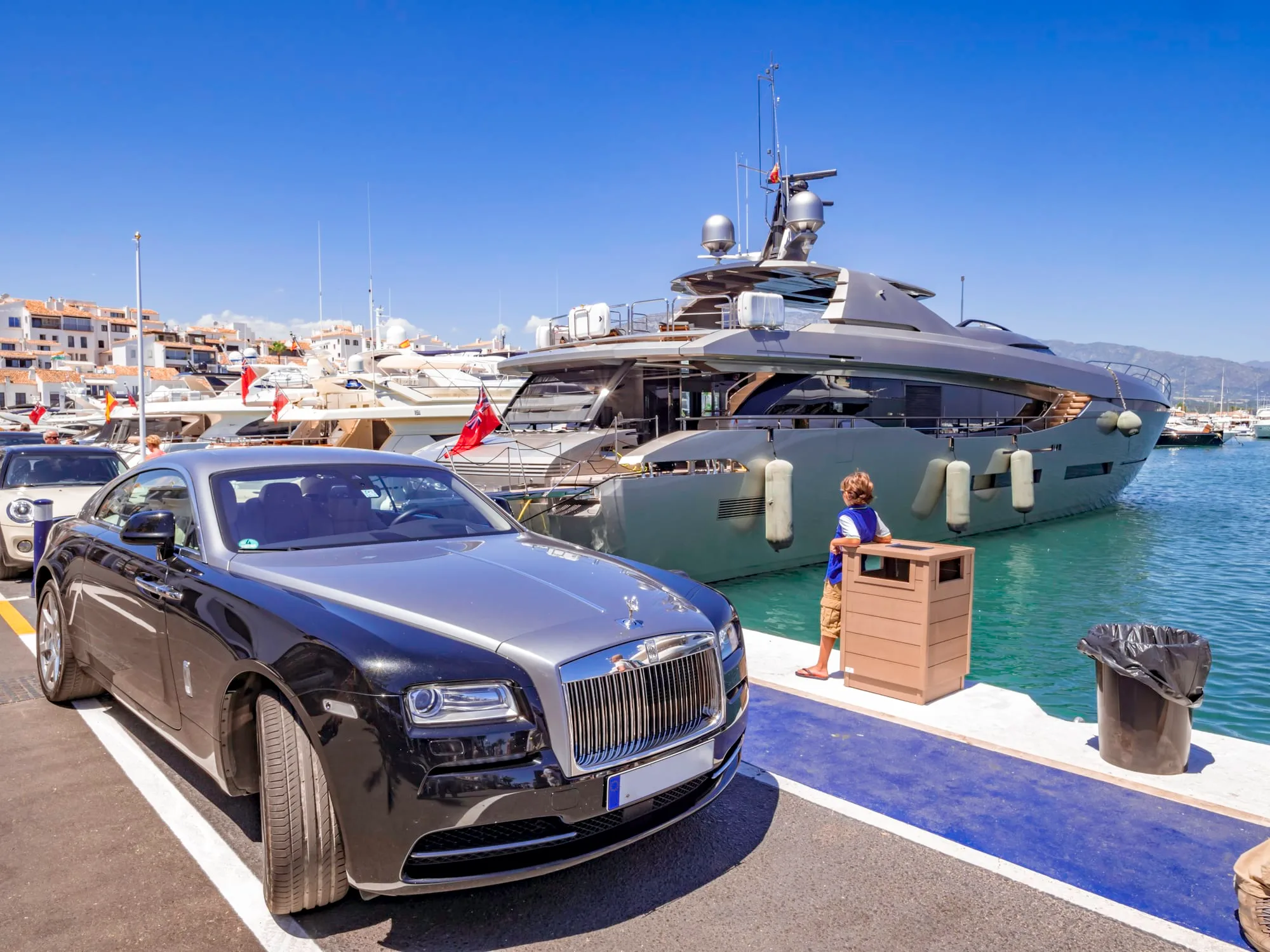 Rolls-Royce car next to a huge yacht in Puerto Banus, Marbella, a luxury harbour and marina in Marbella popular for the jetset