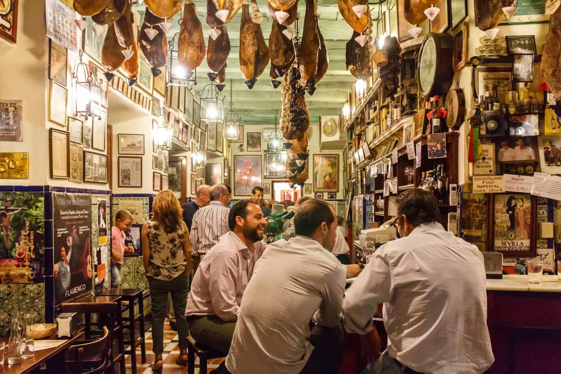 Seville, Spain - Men eating and drinking in a tapas bar in the old city. 