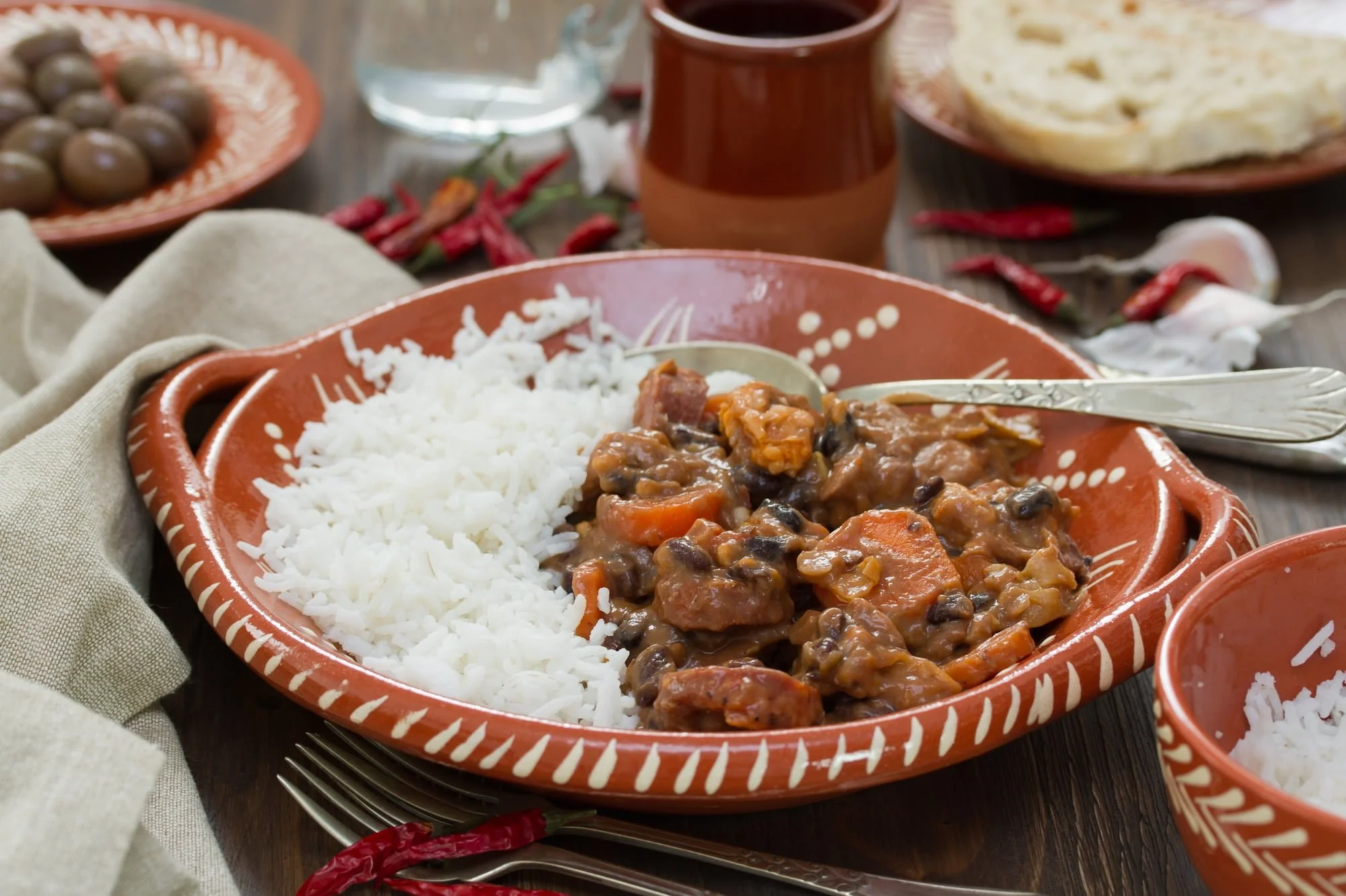 Typical portuguese dishT feijoada with rice in ceramic bowl and red wine on brown background