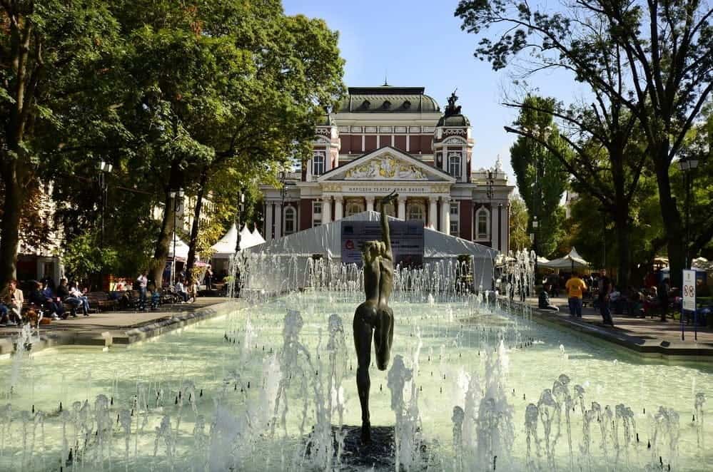 Rejsen går til Bulgarien - Sofia, Bulgaria: Unidentified people relaxing around the pool with small fountains and female sculpture in front of the National Theater Iwan Vazov