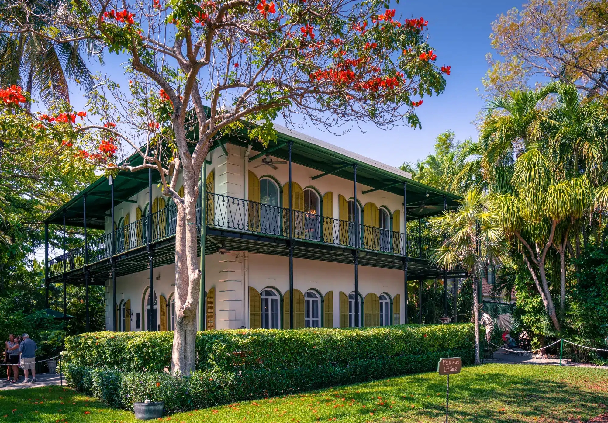 Key West, USA- Ernest Hemingway home in Key West. Beautiful, lime-colored villa in Spanish colonial style with tropical garden around it. Porch and wooden window shades. 