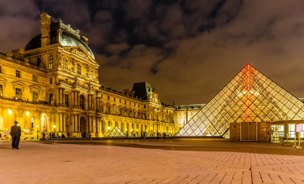 Paris og de utrolige museer - Richelieu wing and the glass pyramid at the Louvre museum at night in Paris, in Ile de France, France