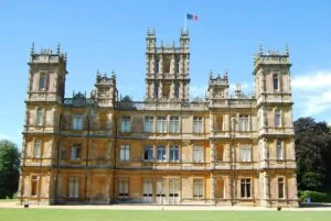 Highclere Castle is a country house in the Jacobean style, with a park designed by Capability Brown. The 5,000-acre estate is in Hampshire, England, United Kingdom, about 5 miles south of Newbury, Berkshire. It is the country seat of the Earl of Carnarvon, a branch of the Anglo-Welsh Herbert family. The architecture is reminiscent of the Houses of Parliament in London. Popular TV show Downton Abbey was largely filmed here and the tour of the castle rooms takes you into many rooms used in the series.