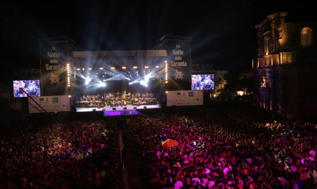 Titusinder af mennesker danser foran scenen til afslutningskoncerten Notte della Taranta i Melpignano i Salento